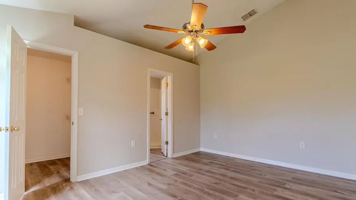 A bedroom with a wooden floor and a ceiling fan.