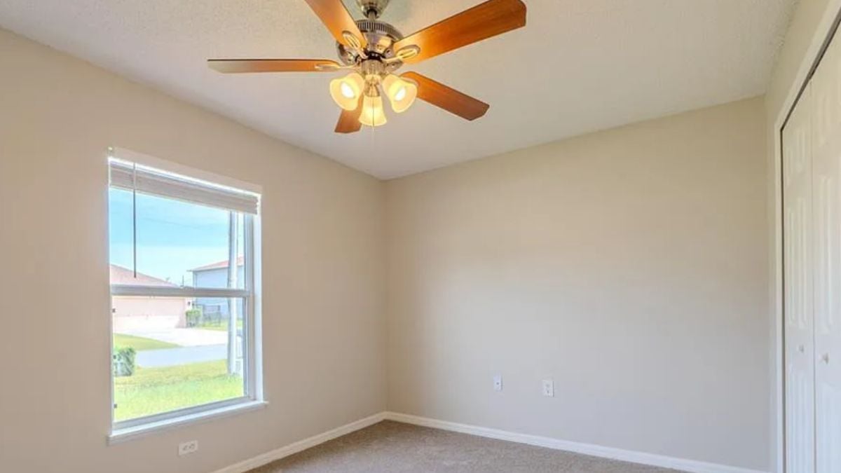 A bedroom with a window and a ceiling fan.