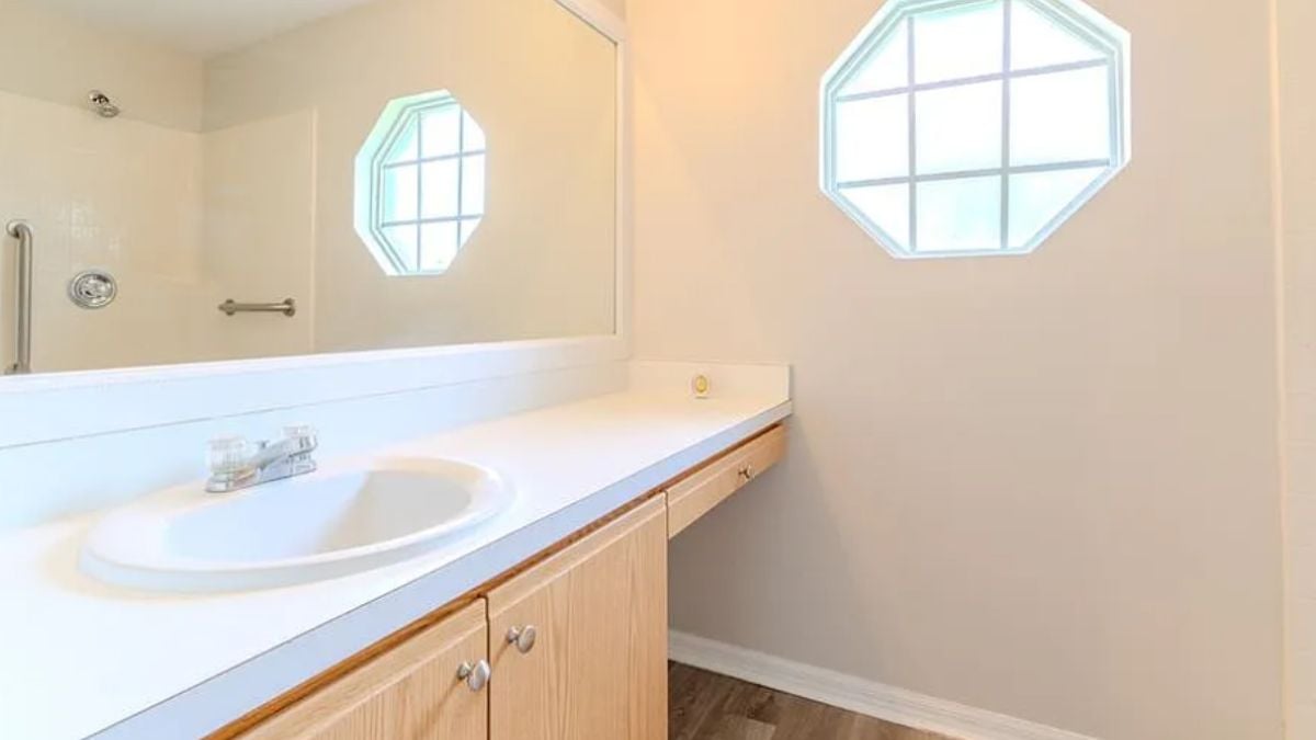A bathroom with a vanity, a mirror, and a window.
