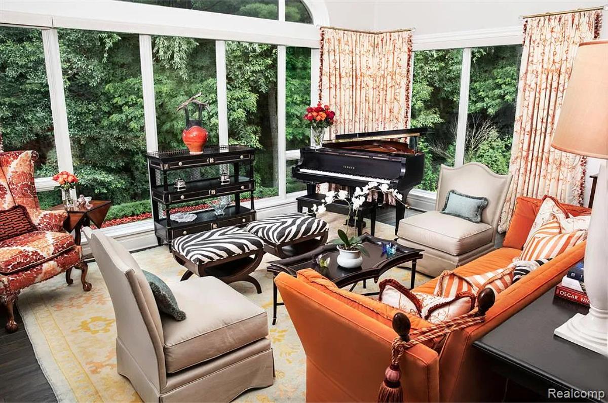 Living room with a piano, glass walls and hardwood doors.