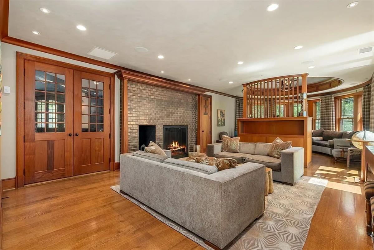 Living room with couches, hardwood floors and a fireplace.