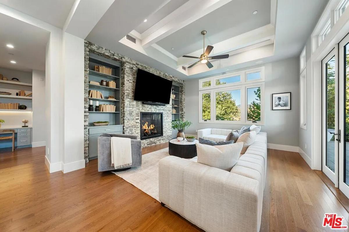 Living room with couches, hardwood floors and a fireplace.
