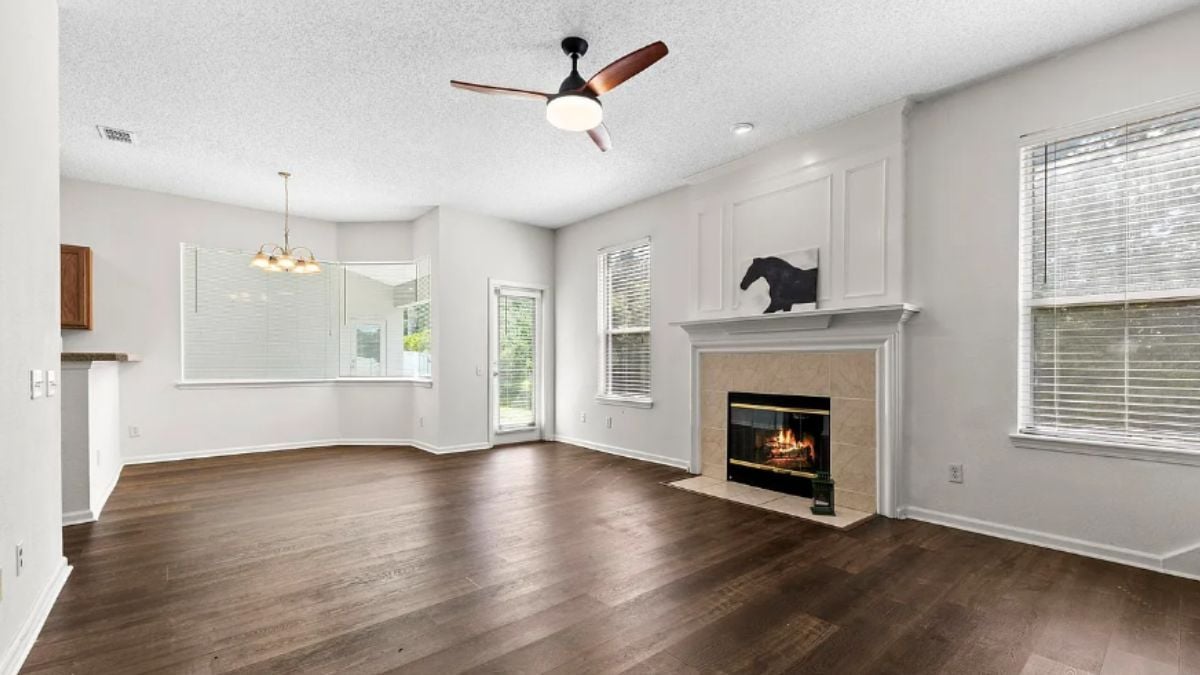 A family room with a ceiling fan, windows, and a fireplace.