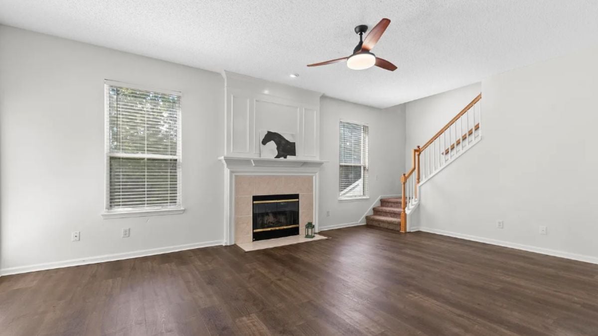 A family room with a ceiling fan, windows, and a fireplace.
