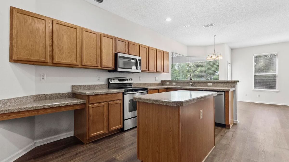 A kitchen with countertops, cabinets, a sink, and kitchen appliances.