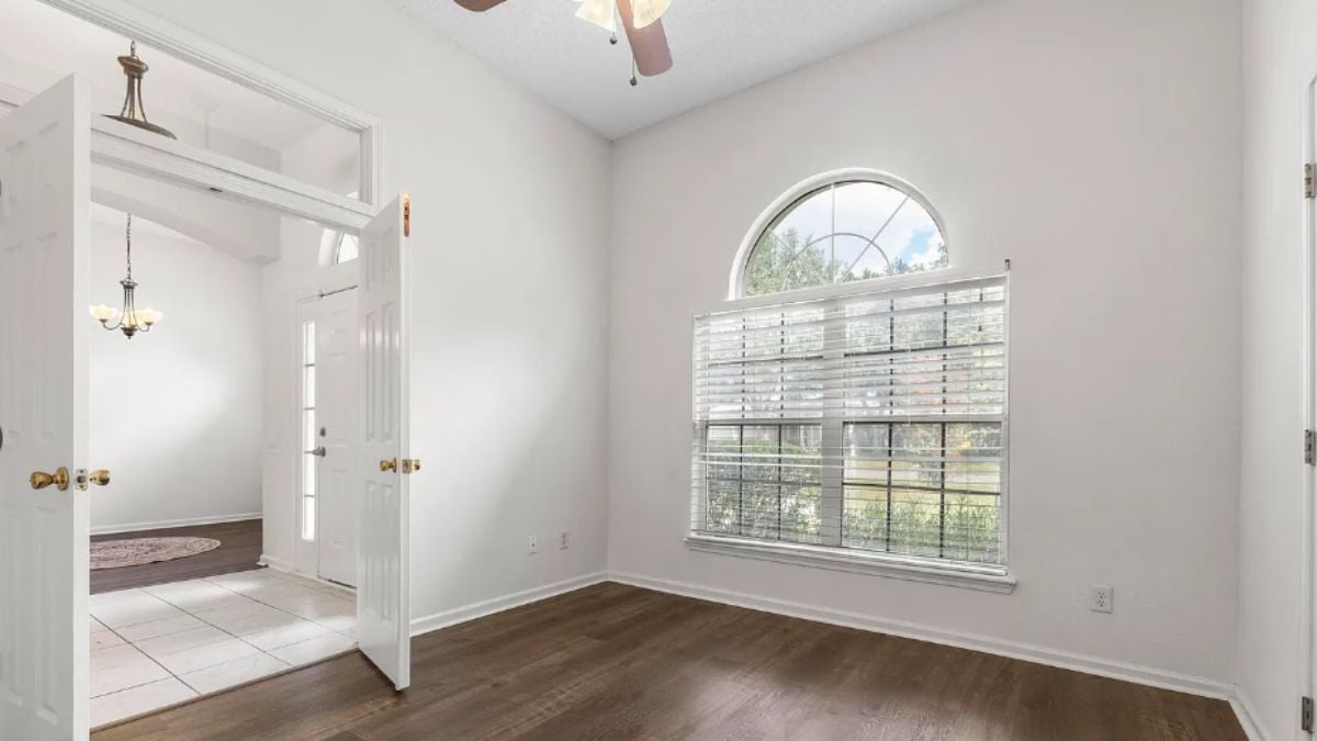 A bedroom with a window and a ceiling fan.