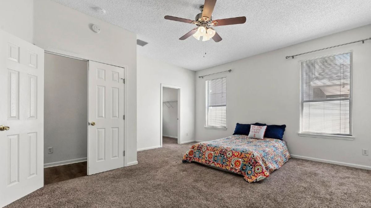 A bedroom with bed, a windows and a ceiling fan.