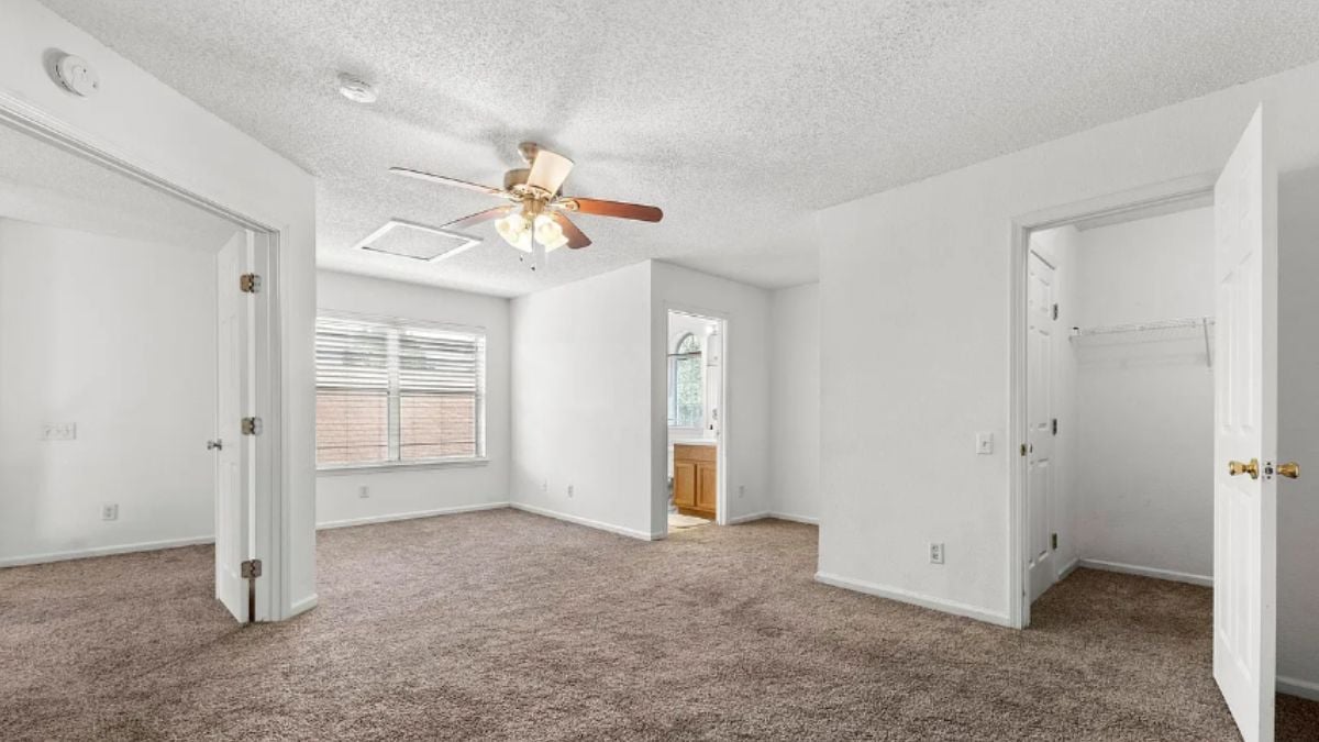 A bedroom with a window and a ceiling fan.