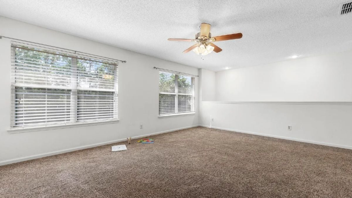 A bonus room with a window and a ceiling fan.