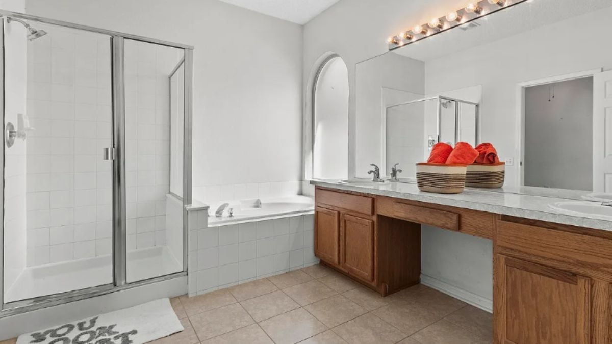 A bathroom with a vanity, shower room, bathtub, and mirror.