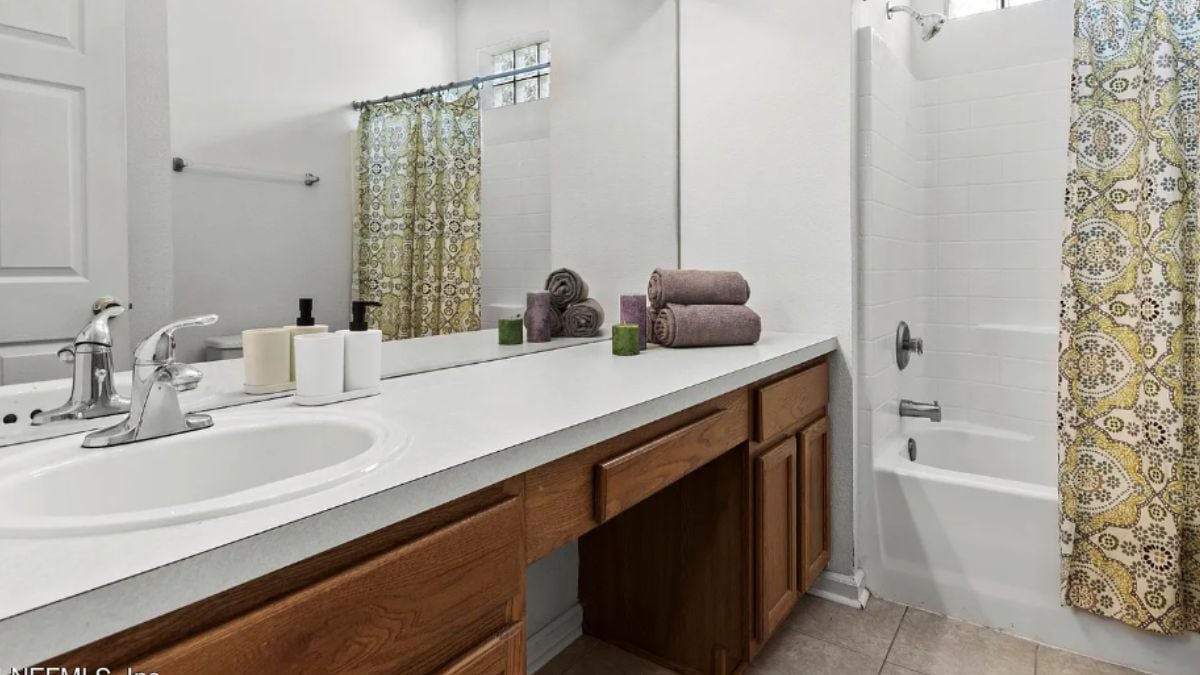 A bathroom with a vanity, bathtub, and mirror.
