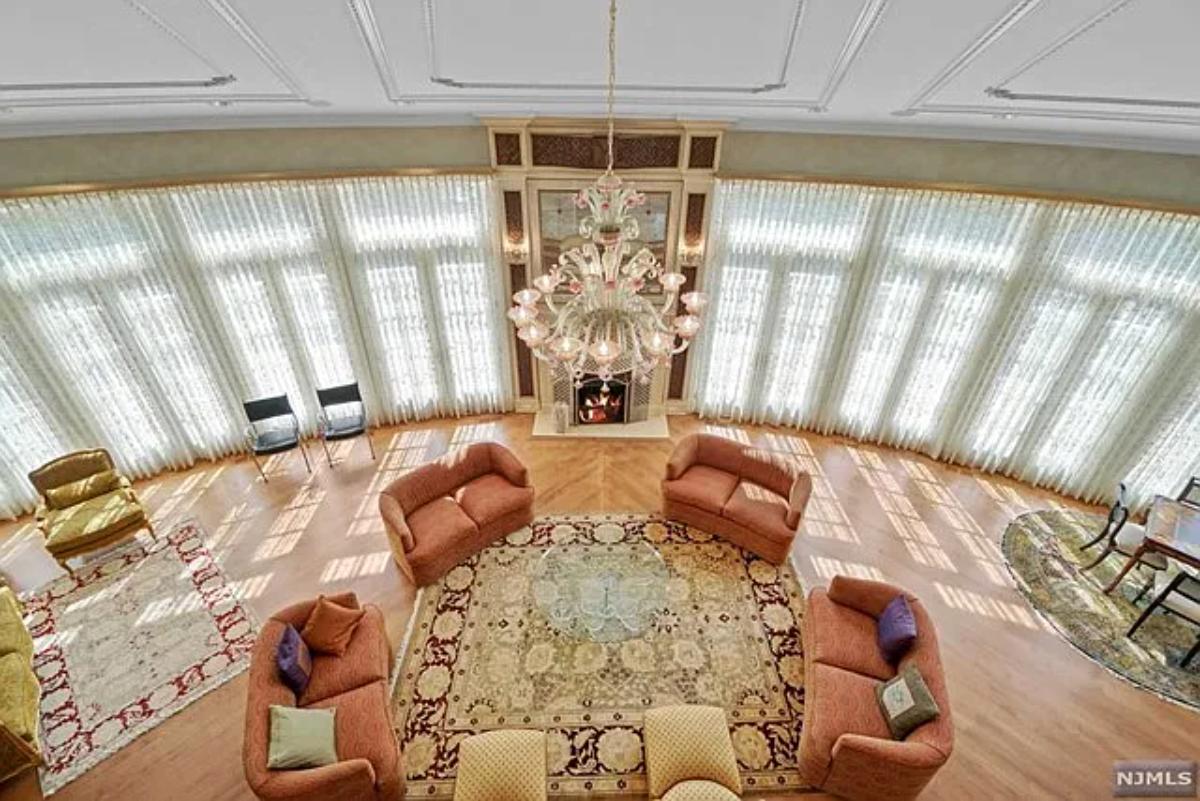 Living room with hardwood flooring, high ceilings and a chandelier.