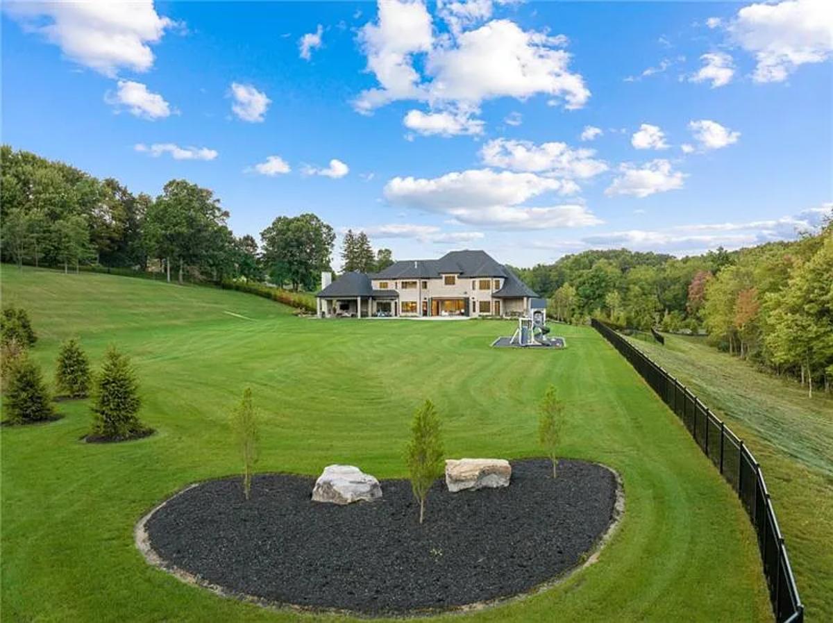 Rear view of the mansion with a large green lawn.