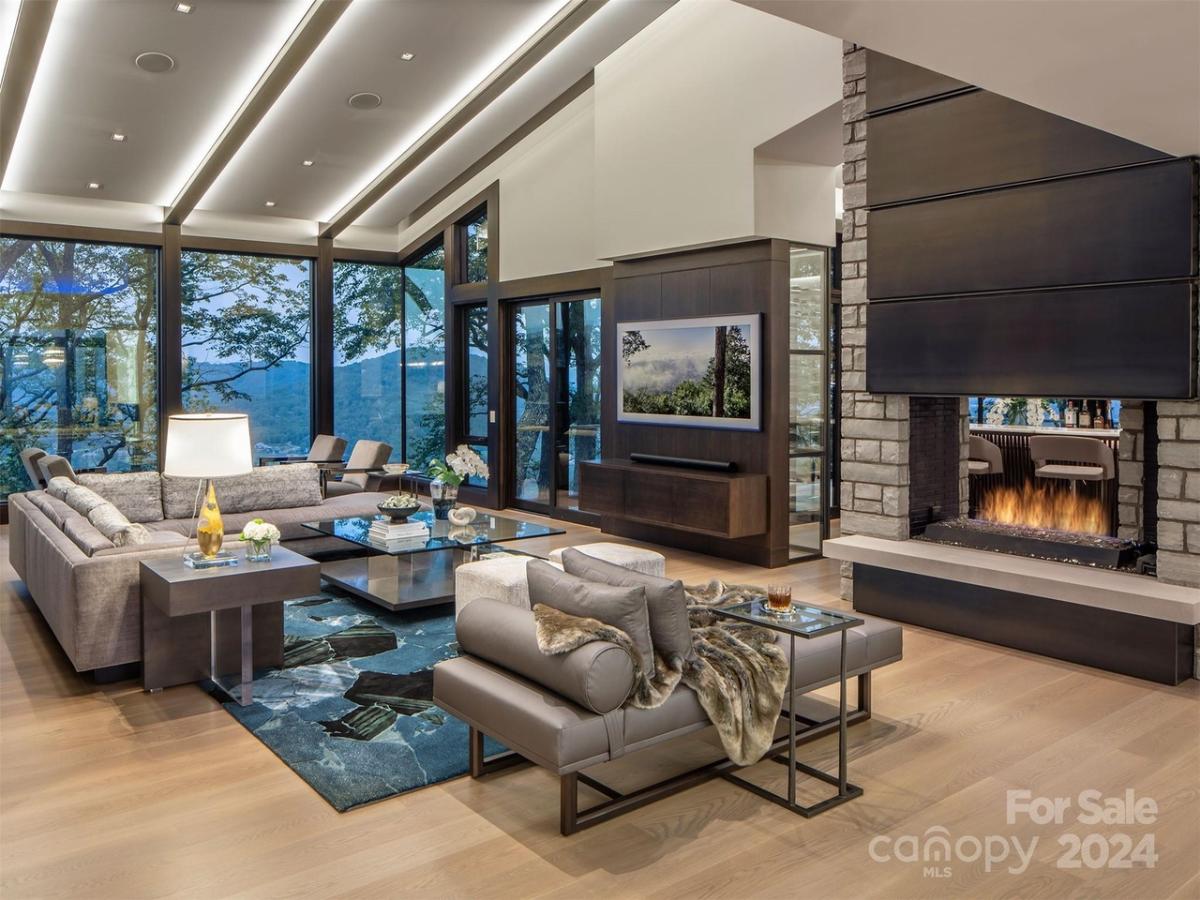 Living room with hardwood flooring, a fireplace and glass walls.