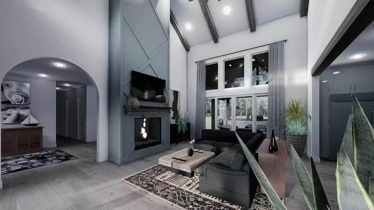 Living room with black sofas, a fireplace, and a vaulted ceiling lined by exposed beams.