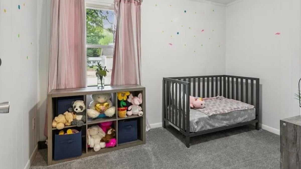 A bedroom with a window, cubbies, and a crib.