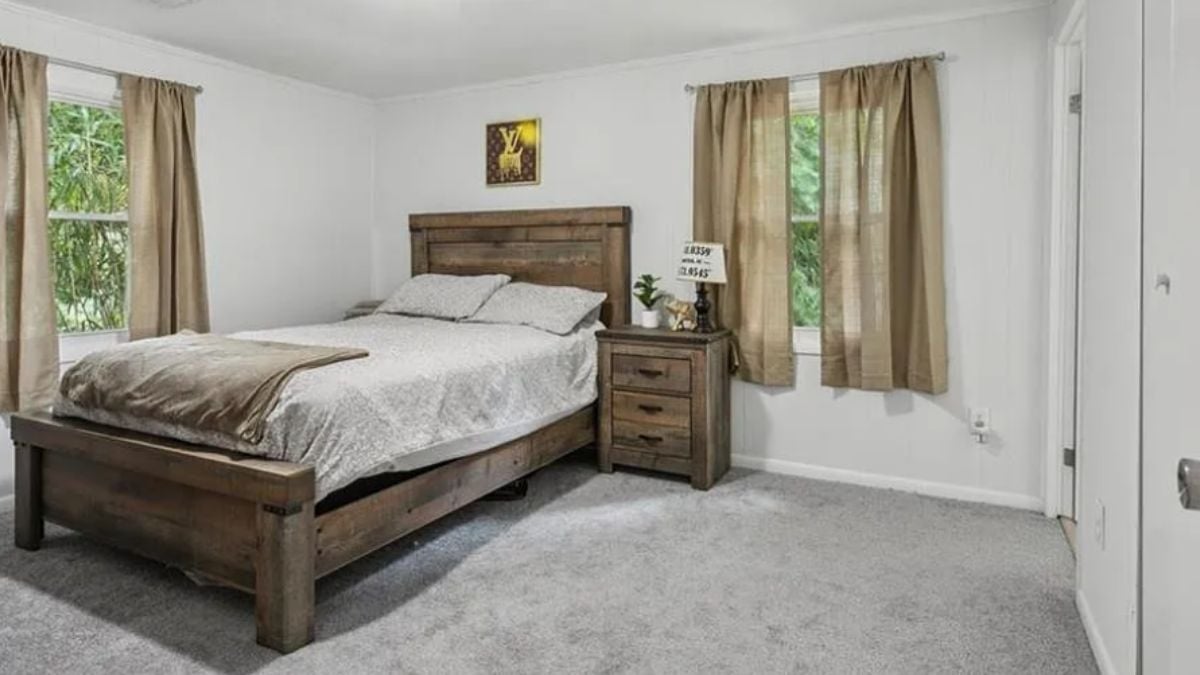 A bedroom with a bed, windows, and nightstands.