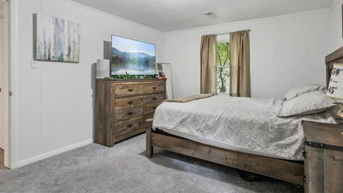 A bedroom with a bed, a window, a cabinet, a TV, and a nightstand.