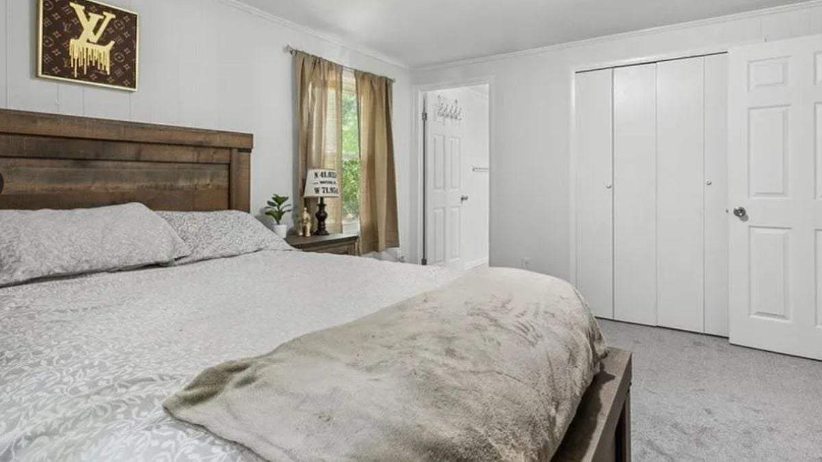 A bedroom with a bed, a window, and a nightstand.