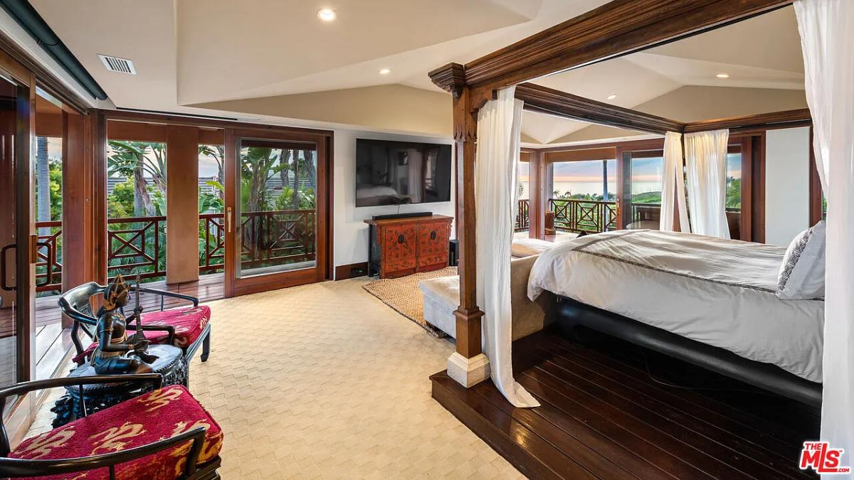 Bedroom with a large bed, glass windows and carpet flooring.