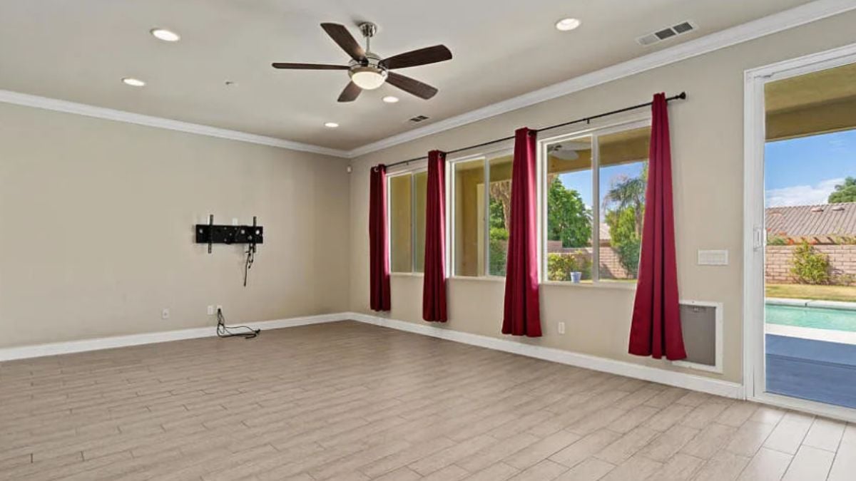 A living room with a ceiling fan and windows.