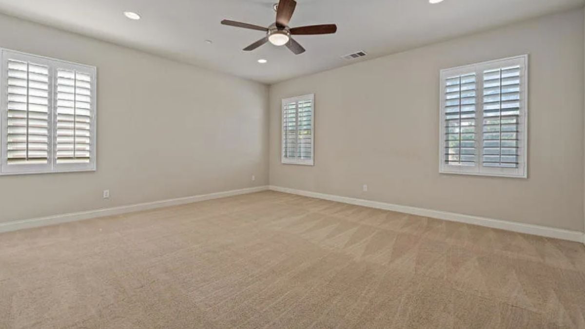A bedroom with windows and a ceiling fan.