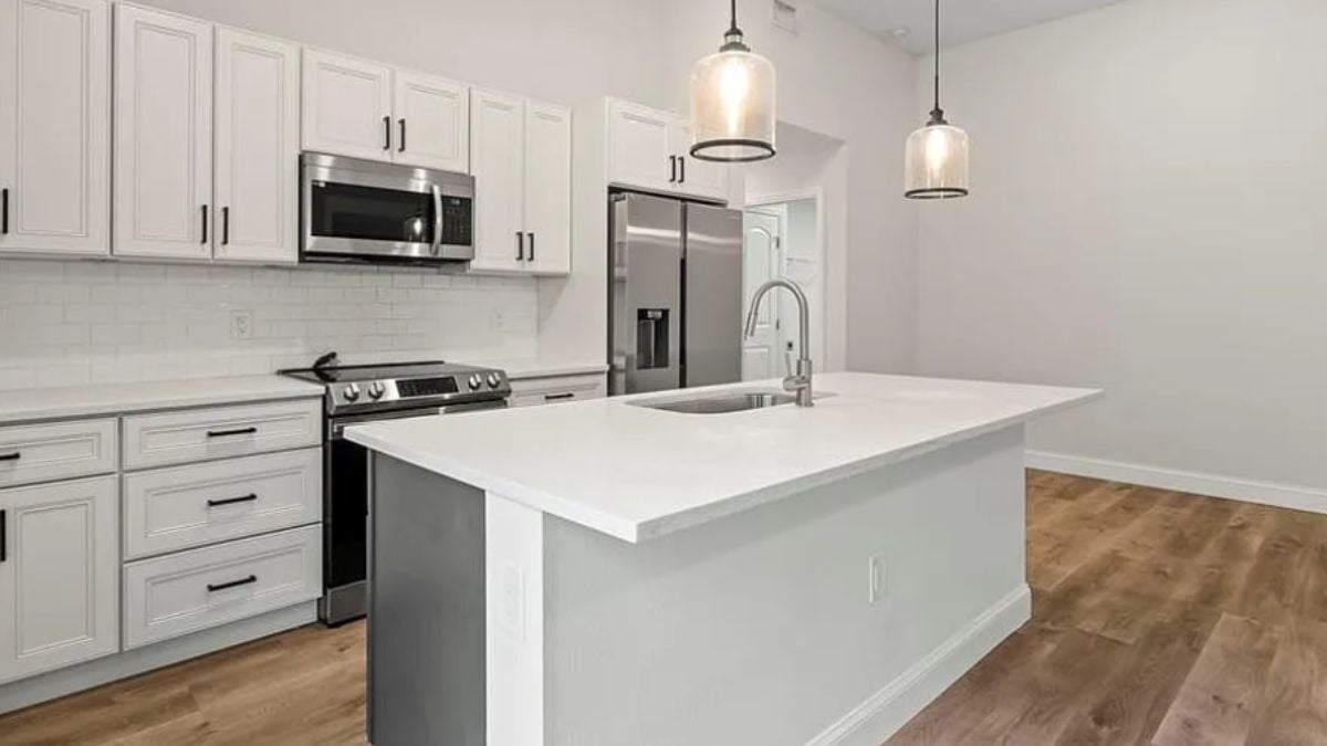 A kitchen with countertops, a sink, cabinets, and kitchen appliances.