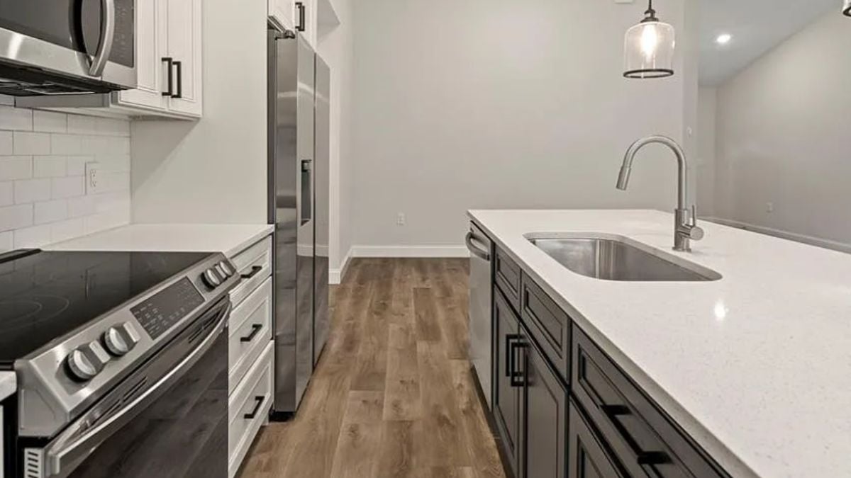 A kitchen with countertops, a sink, cabinets, and kitchen appliances.