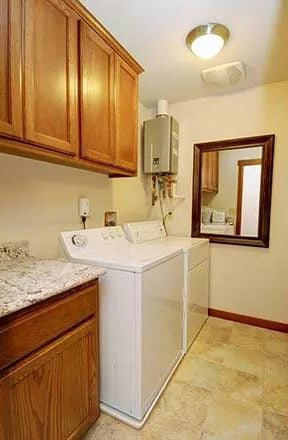 Laundry room with wooden cabinets and top-load appliances.