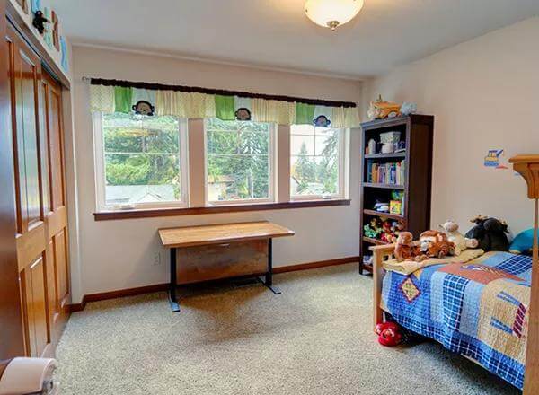 Bedroom with a carpeted floor and triple windows.