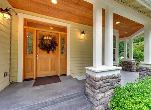 Entry porch with a wooden front door and stone base columns.