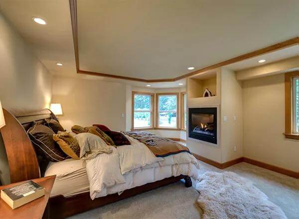 Primary bedroom with a wooden bed, a fireplace, and a bay window.