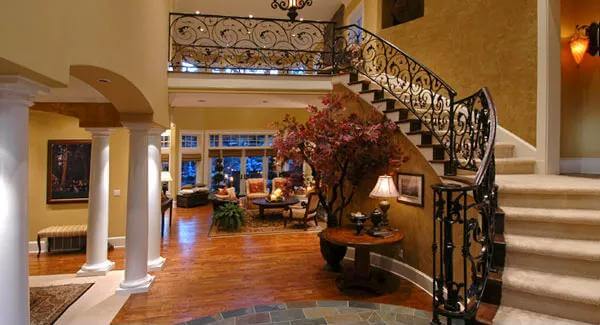 Foyer with a curved staircase framed by intricate wrought iron railings.