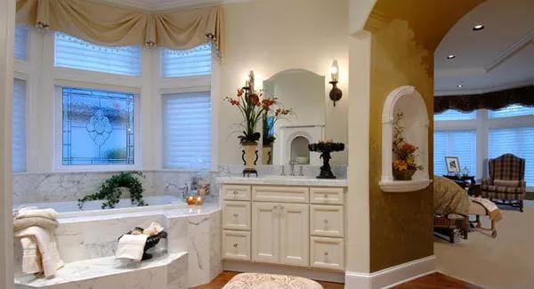 Primary bathroom with a white vanity and a marble tub against the bay window.