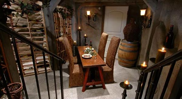 Wine cellar with a wooden table, high back chairs, and wooden wine racks.