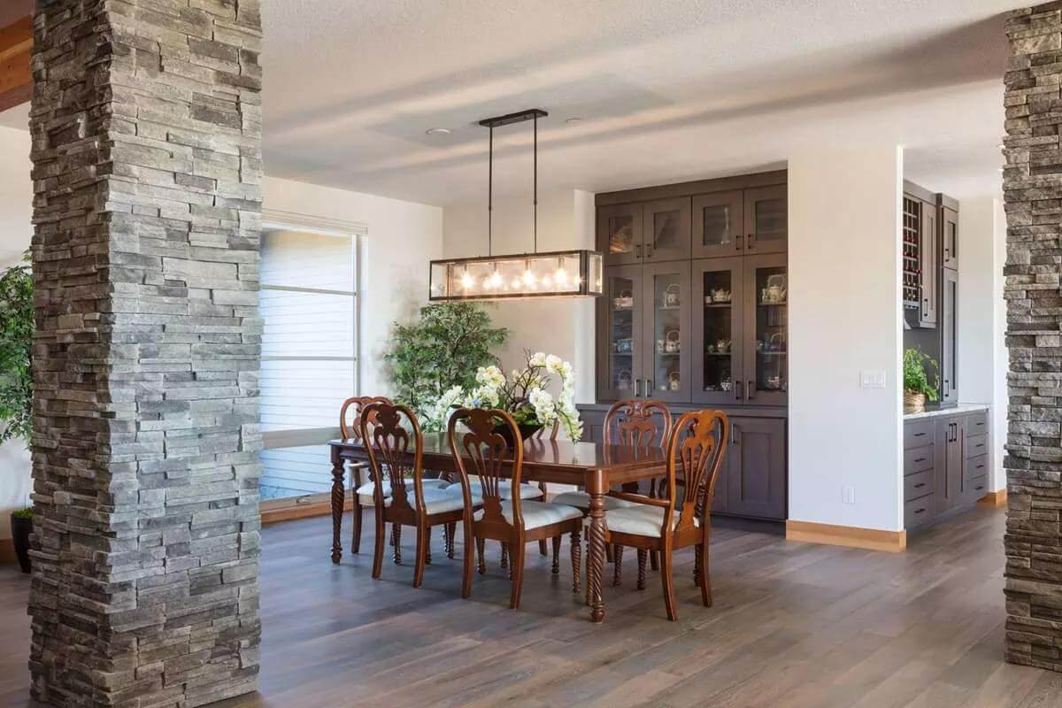 Dining room with a display cabinet and a dark wood dining set illuminated by a linear chandelier.