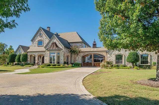 Angled front view with a stone exterior and a covered entry porch framed by archways.
