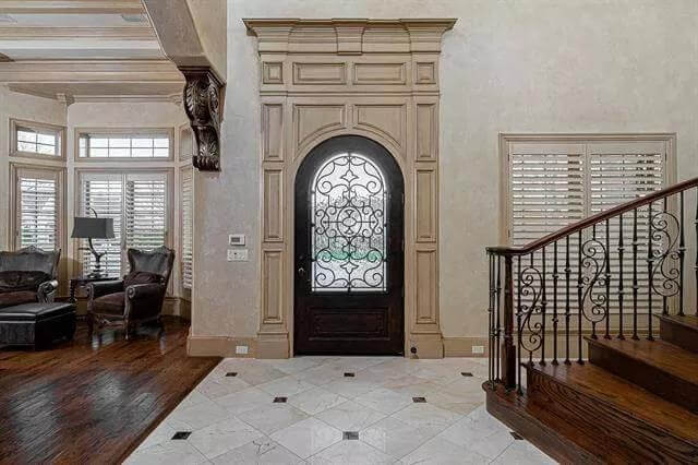 Foyer with an arched front door and a staircase framed by ornate railings.
