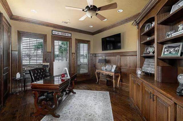 Office with a built-in bookcase, a dark wood desk, and wooden wainscoting.