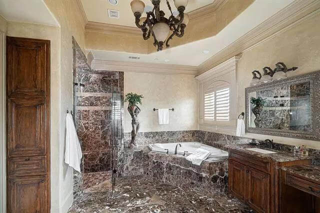 Primary bathroom with a wooden vanity, a corner tub, and a tiled shower.