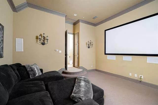 Media room with a black sofa and a large projector screen.