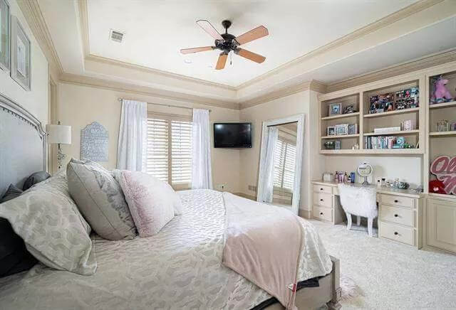 Bedroom with a tray ceiling, a built-in vanity, and a full-length mirror over the carpeted floor.