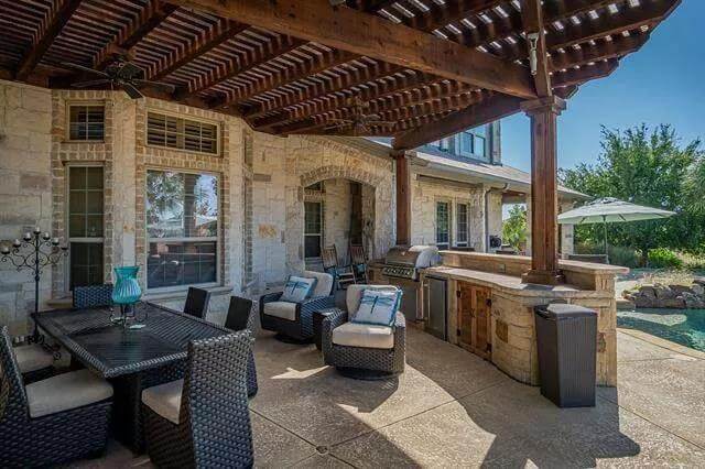 Outdoor lounge with a wicker dining set and a summer kitchen.