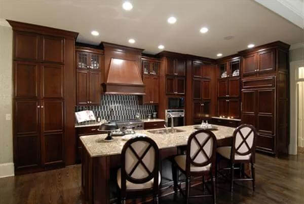 Kitchen with dark wood cabinets and a matching island with seating for three.