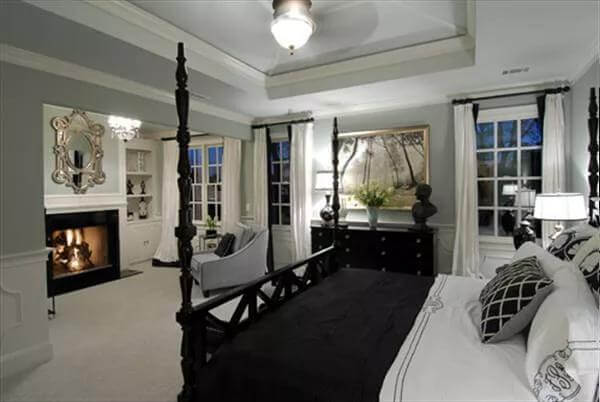 Primary bedroom with a fireplace and a four-poster bed under a tray ceiling.