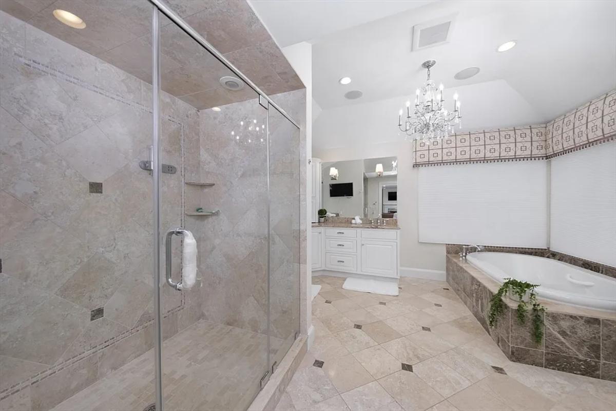 Bathroom with a chandelier, a soaking tub and a walk-in shower.