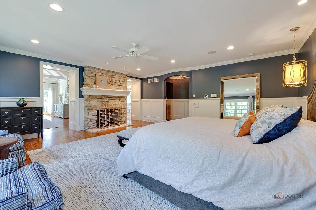 Bedroom with a large bed, a fireplace and hardwood floors.
