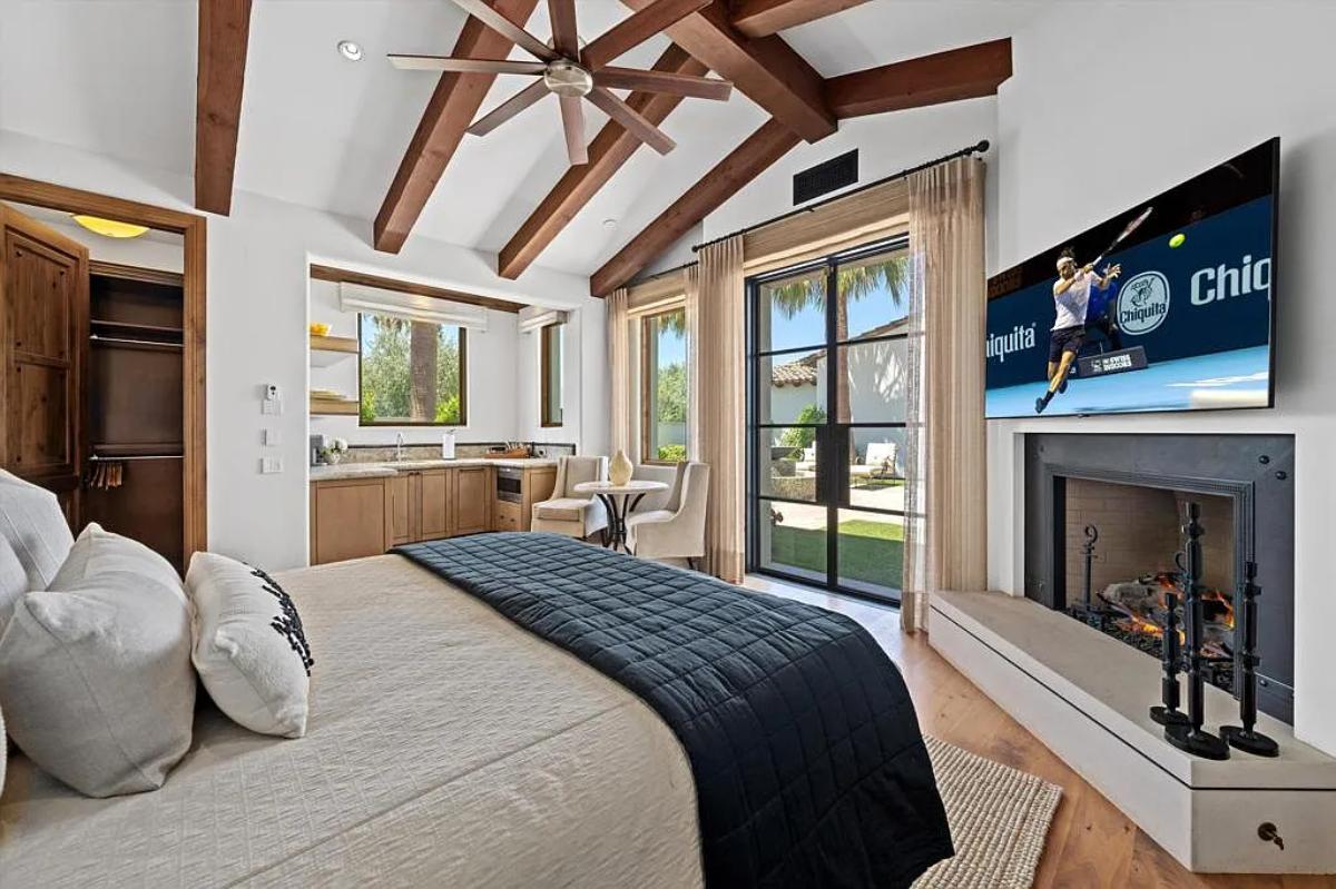 Bedroom with a large bed, a fireplace and hardwood floors.