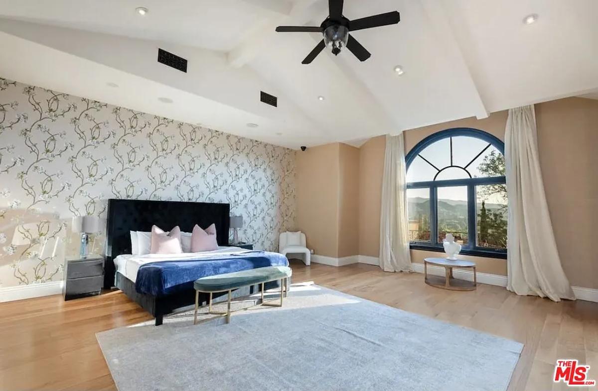 Bedroom with a large bed, glass windows and hardwood floors.