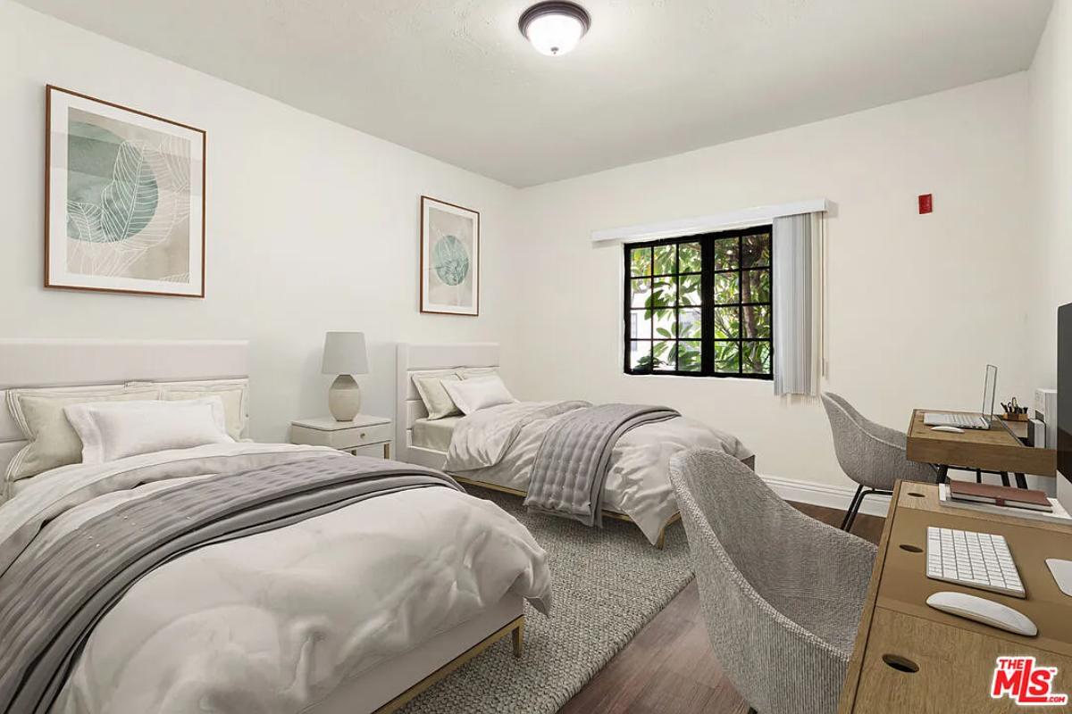 Bedroom with two beds and hardwood floors.